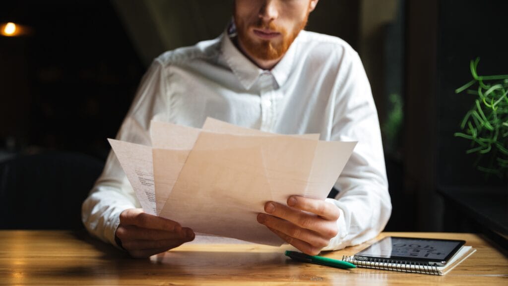 cropped photo of young readhead bearded man working with papers